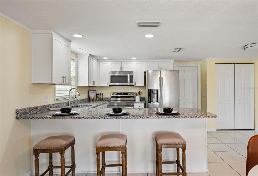 7401 Islander Lane Hudson, FL 34667 - Photo 10 of 30 a kitchen with stainless steel appliances granite countertop a refrigerator a sink a stove a microwave and white cabinets with wooden floor