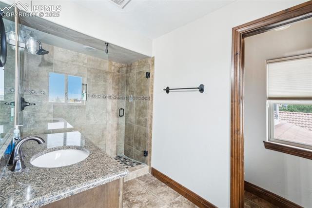 13665 Random Ridge View Colorado Springs, CO 80921 - Photo 31 of 49 Bathroom featuring vanity, a shower with shower door, and tile patterned flooring