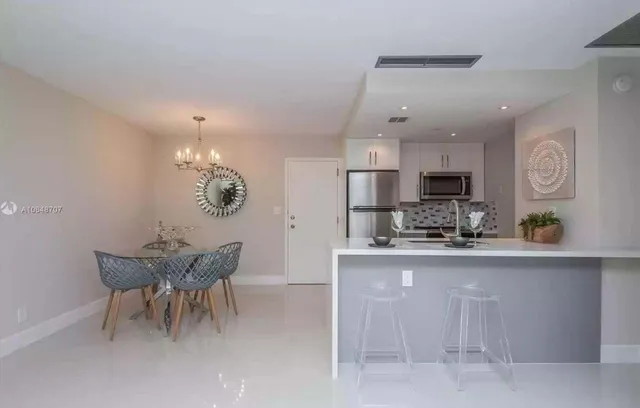 a kitchen with stainless steel appliances kitchen island granite countertop a table and chairs in it