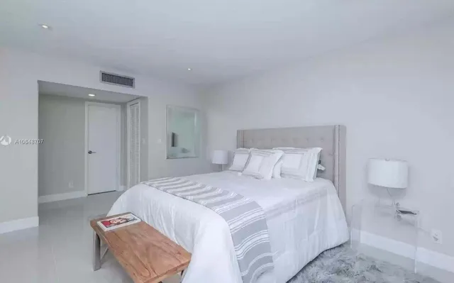 a spacious bedroom with a bed and mirror