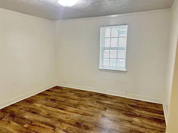 an empty room with wooden floor and cabinet