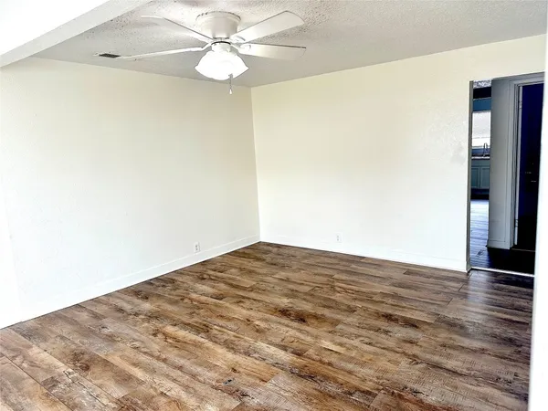 a view of empty room with wooden floor and fan