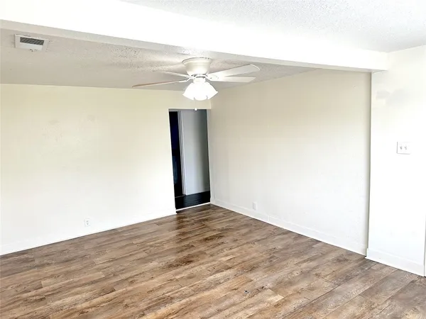 an empty room with wooden floor ceiling fan and windows