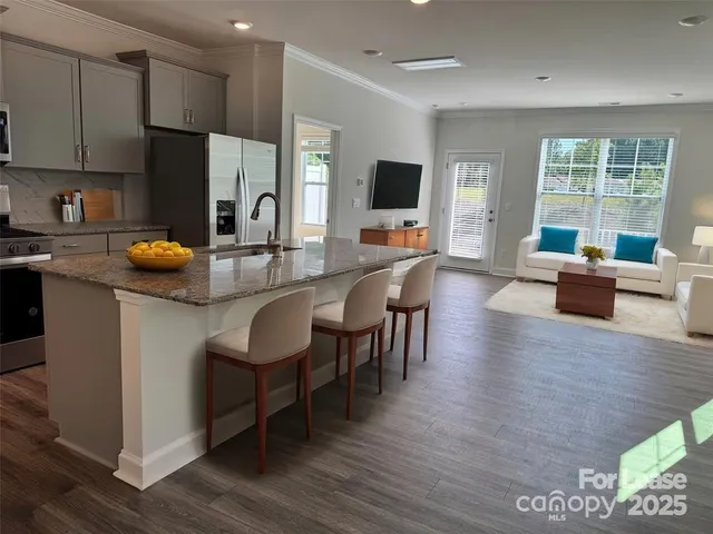 a kitchen with stainless steel appliances granite countertop a stove top oven a sink dishwasher a dining table and chairs with wooden floor