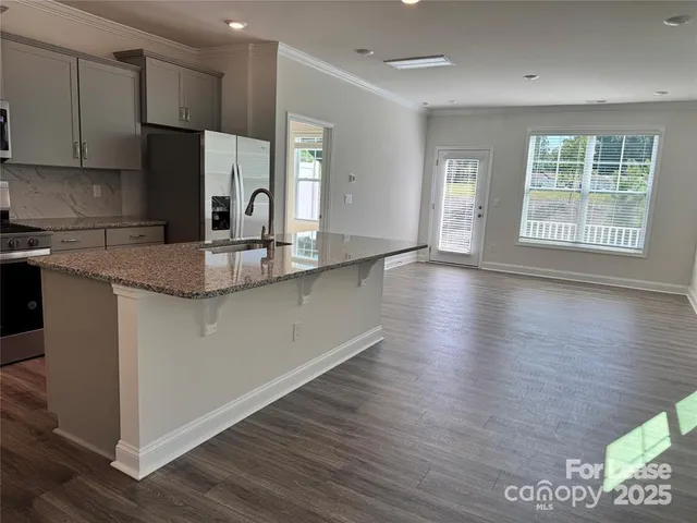 a kitchen with stainless steel appliances granite countertop a sink window and cabinets