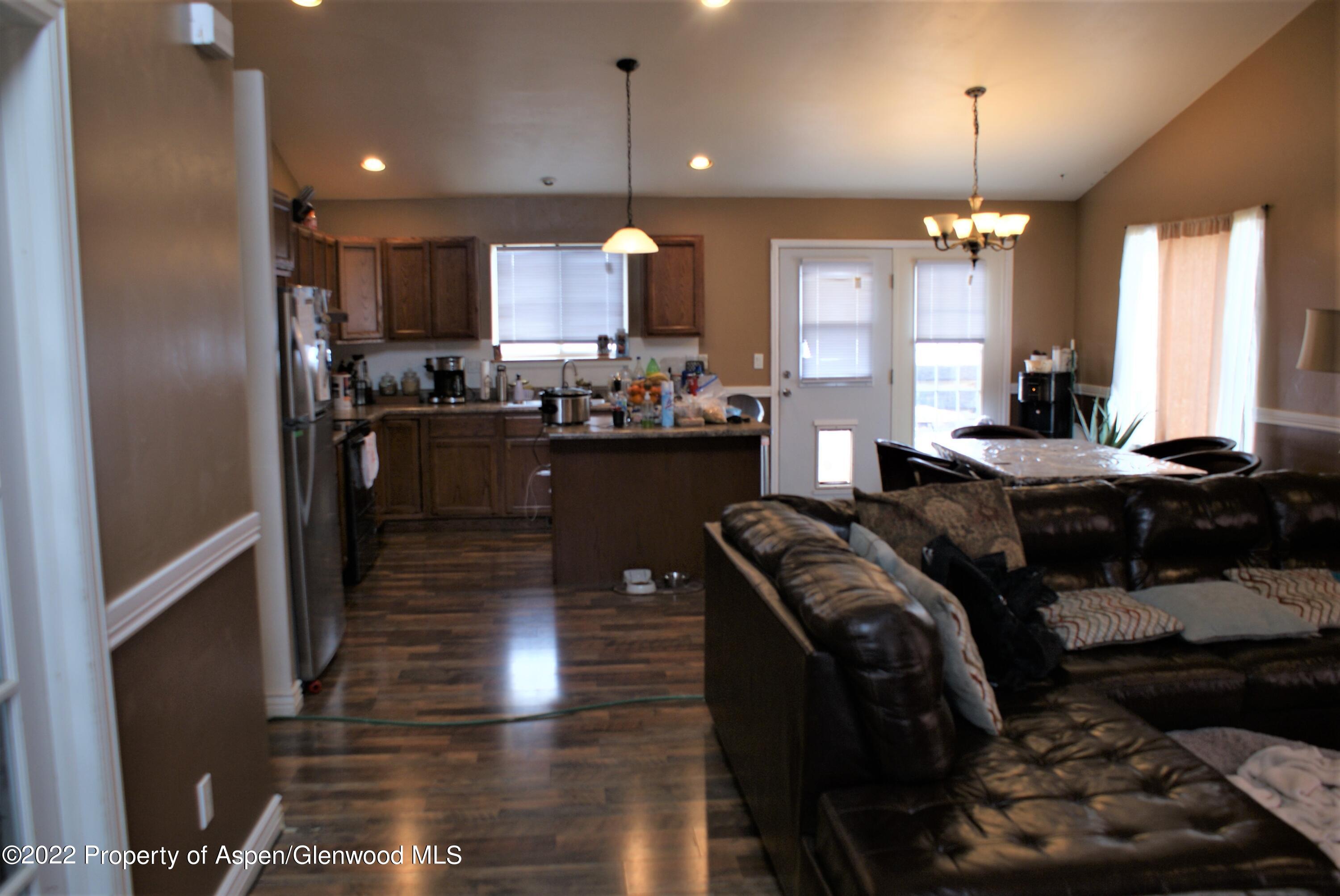 1355 Firethorn Drive Rifle, CO 81650 - Photo 5 of 9 a kitchen with stainless steel appliances kitchen island granite countertop a refrigerator a stove a sink and a dining table with wooden floor