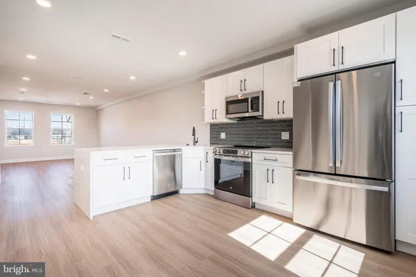 a kitchen with white cabinets stainless steel appliances and wooden floor