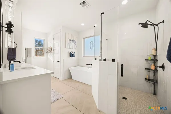 a large white bathroom with a shower a sink and a mirror
