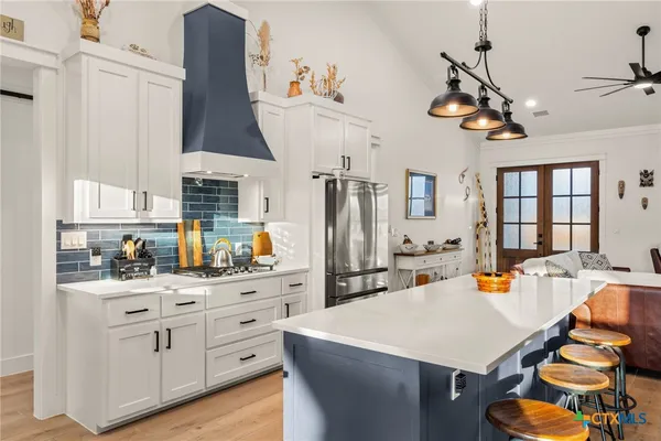 a kitchen with stainless steel appliances kitchen island granite countertop a table chairs in it and a window