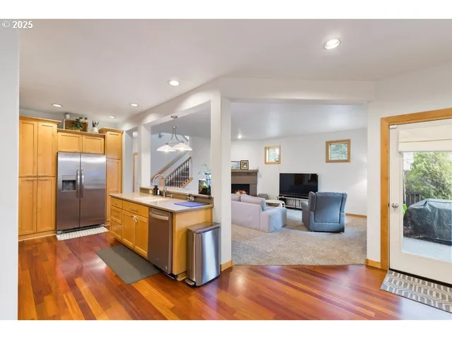 a living room with stainless steel appliances kitchen island granite countertop furniture and a wooden floor