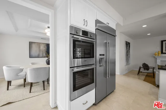 a living room with furniture a flat screen tv and a refrigerator