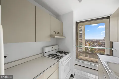 a kitchen with a stove and a view of living room