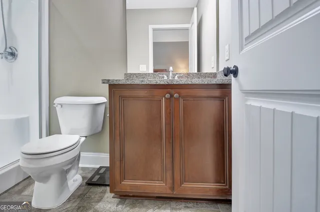 a bathroom with a granite countertop sink a toilet and shower