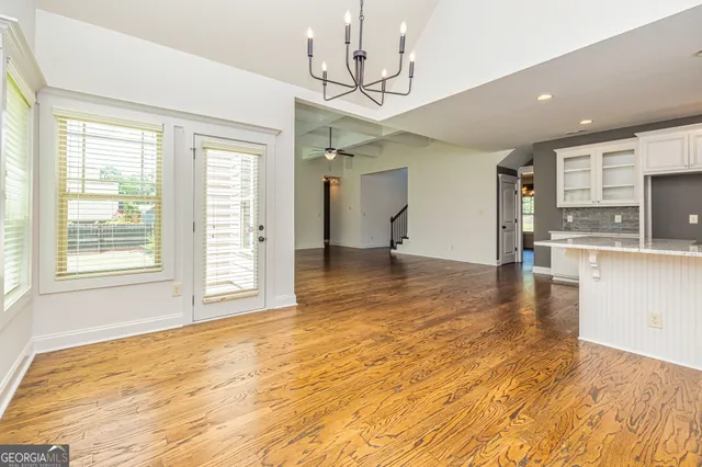 a view of an empty room with kitchen and window