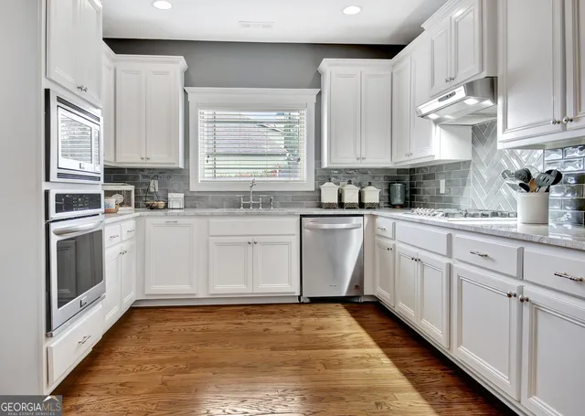 a kitchen with white cabinets appliances and a sink