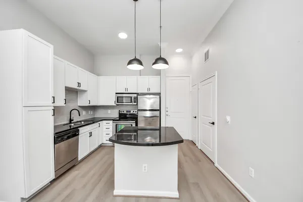 a kitchen with stainless steel appliances granite countertop a sink a stove a refrigerator and island with wooden floor