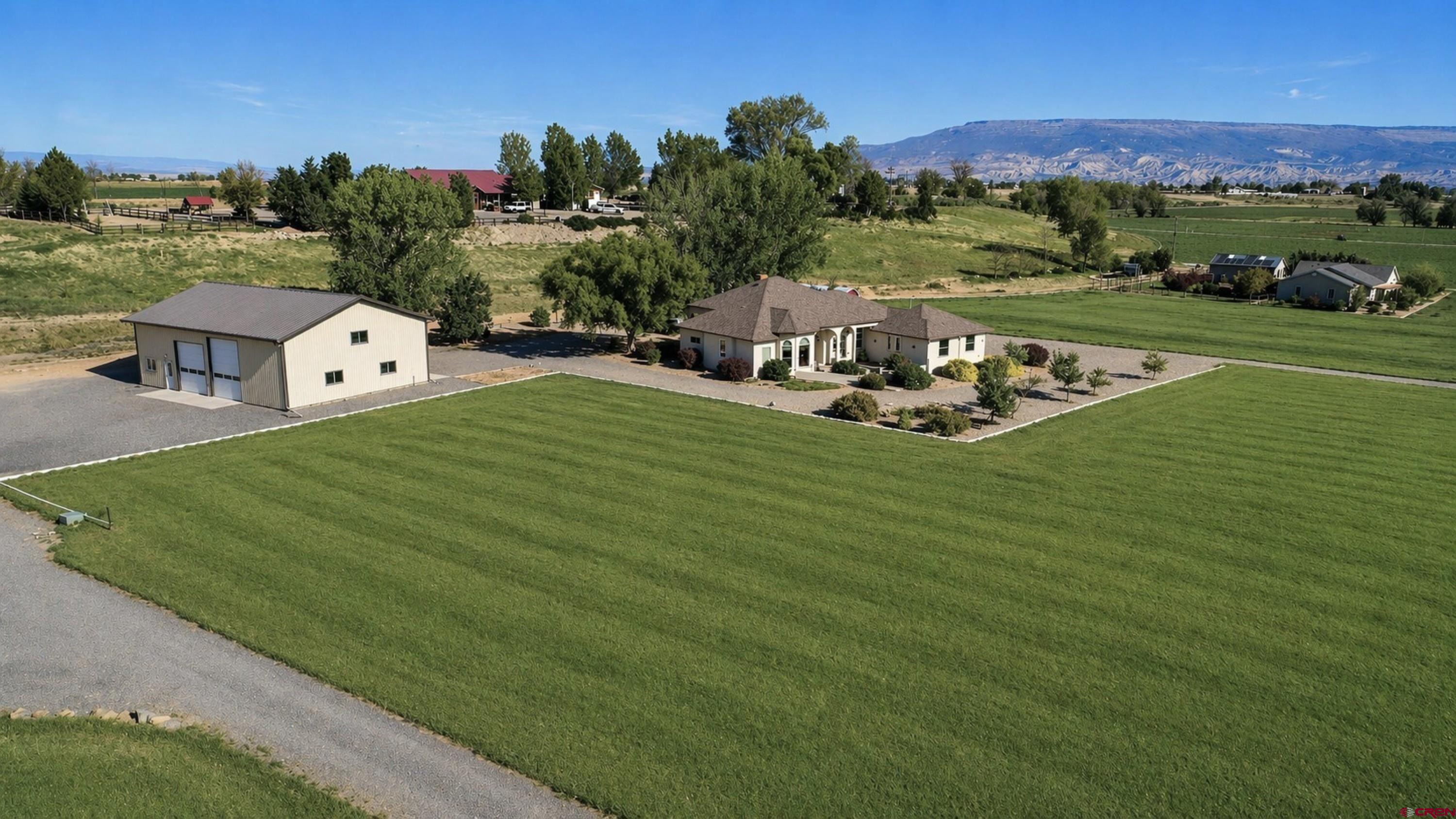 a view of a white house with a big yard and mountain view