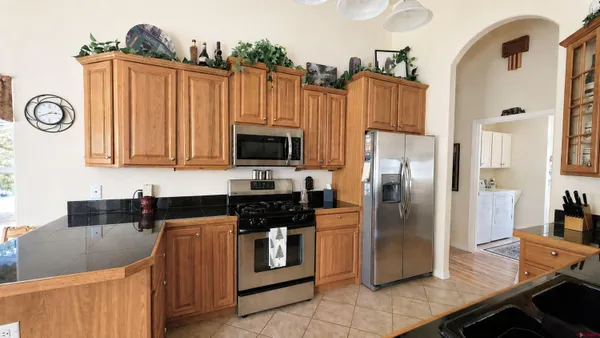 a kitchen with granite countertop a refrigerator a stove and a sink with wooden floor