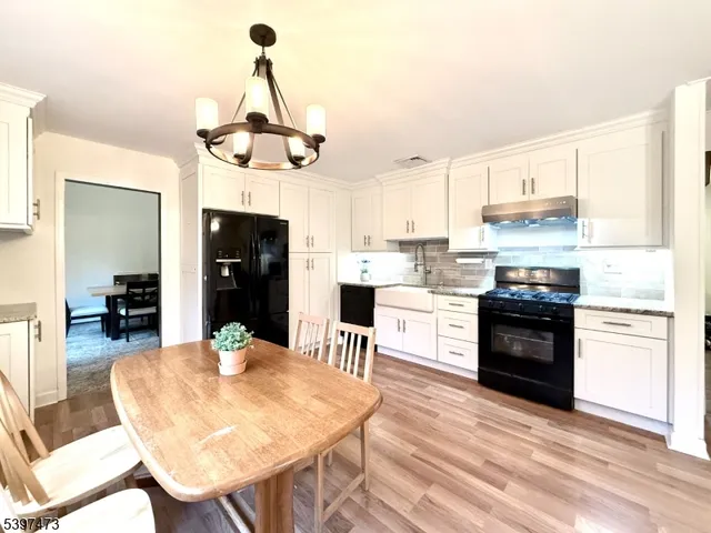 a kitchen with stainless steel appliances kitchen island granite countertop a dining table and chairs a refrigerator with wooden floor