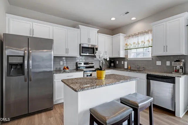 a kitchen with stainless steel appliances granite countertop a refrigerator a sink a stove a microwave and island