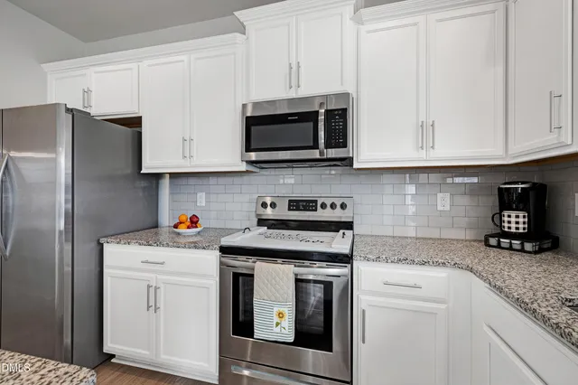 a kitchen with granite countertop white cabinets and stainless steel appliances
