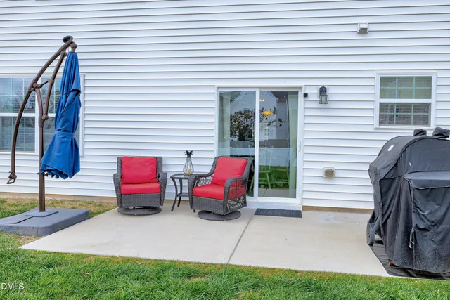 a view of two chairs and table in the back yard of the house