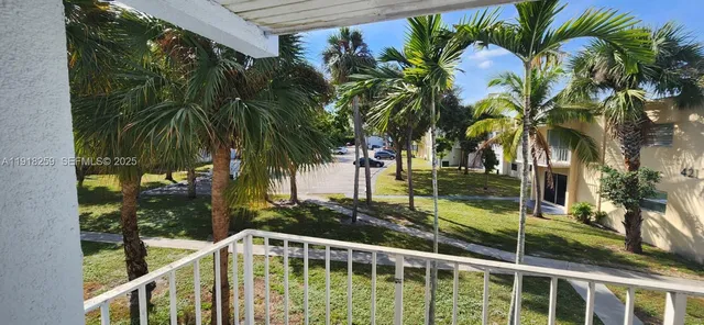 a view of balcony with a yard and palm trees