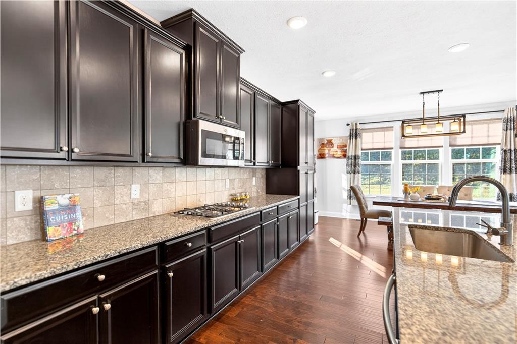 1444 Main Street Pittsburgh, PA 15241 - Photo 18 of 50 a kitchen with stainless steel appliances granite countertop a stove top oven a sink dishwasher a dining table and chairs with wooden floor