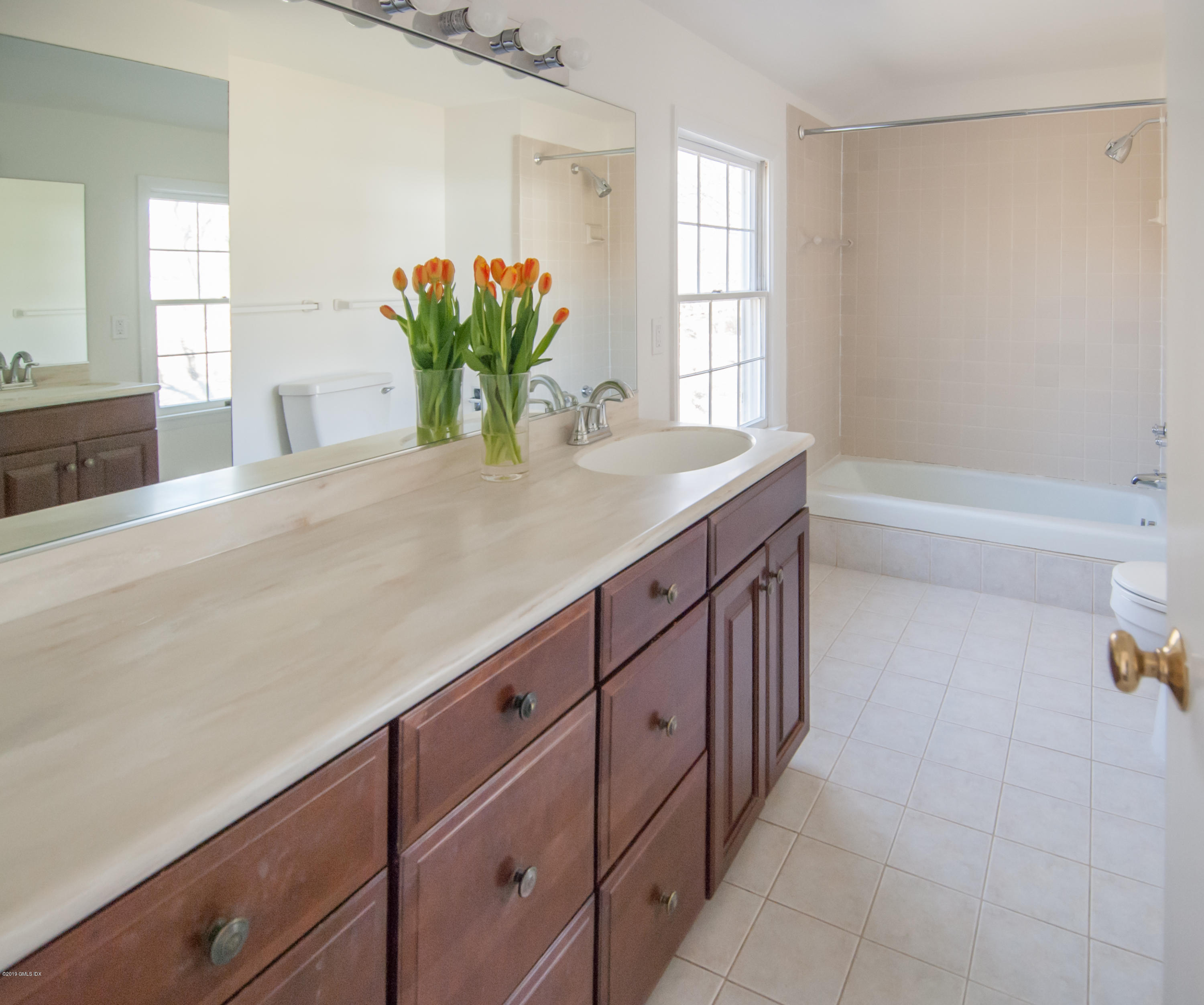 25 Harkim Road Greenwich, CT 06831 - Photo 9 of 14 a bathroom with a granite countertop sink a mirror and a bathtub