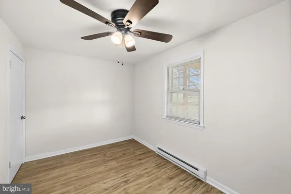 an empty room with wooden floor chandelier fan and windows