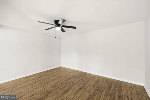 a view of a room with wooden floor and a ceiling fan