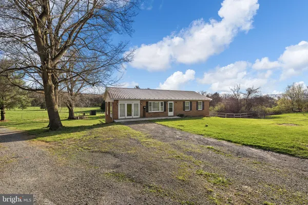 a view of a house with a big yard and large trees