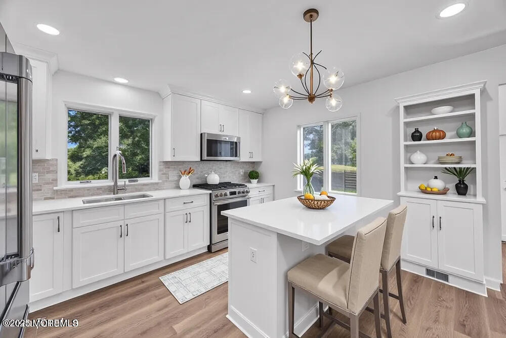 717 Holmdel Road Holmdel, NJ 07733 - Photo 17 of 39 a kitchen with stainless steel appliances granite countertop a sink a stove a refrigerator cabinets and a dining table with wooden floor