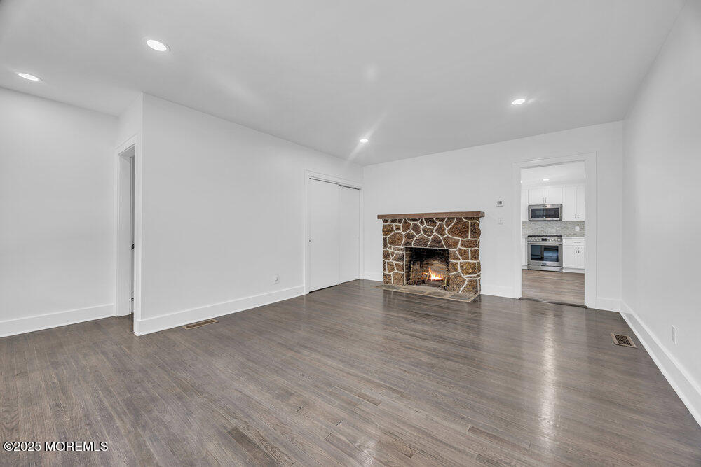 717 Holmdel Road Holmdel, NJ 07733 - Photo 8 of 39 an empty room with wooden floor and fireplace