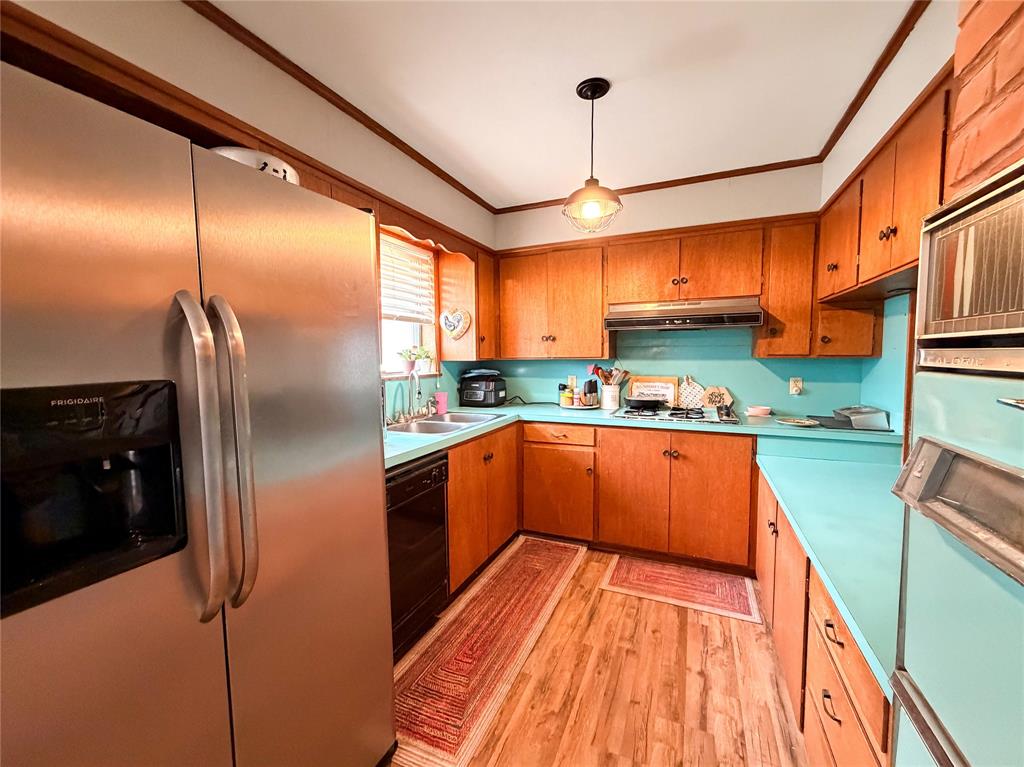 1706 North Ave H Haskell, TX 79521 - Photo 13 of 25 a kitchen with stainless steel appliances a refrigerator a sink and wooden cabinets