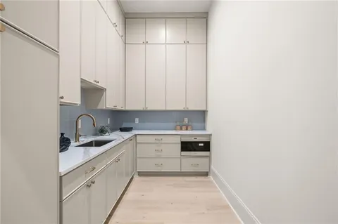 a kitchen with white cabinets and sink