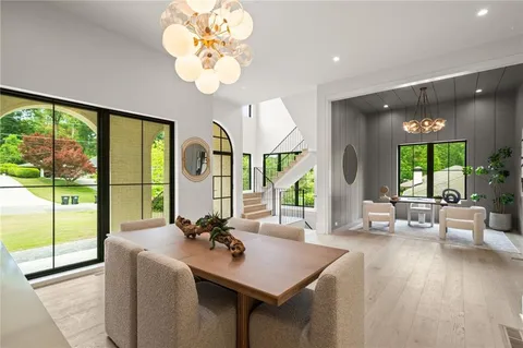 a view of a dining room with furniture a chandelier and large windows