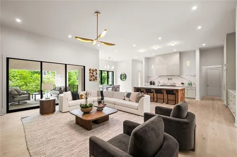 a living room with furniture kitchen view and a large window