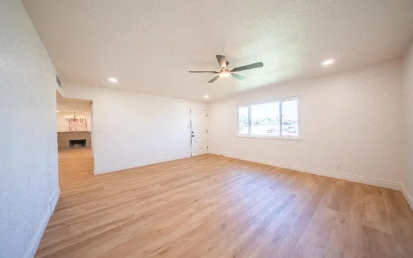 a view of an empty room with a window and wooden floor