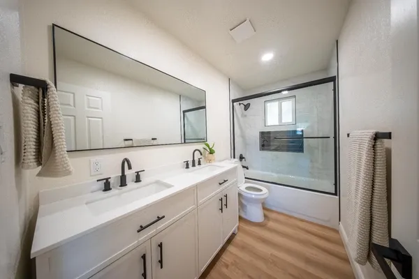 a bathroom with a double vanity sink toilet mirror and bathtub