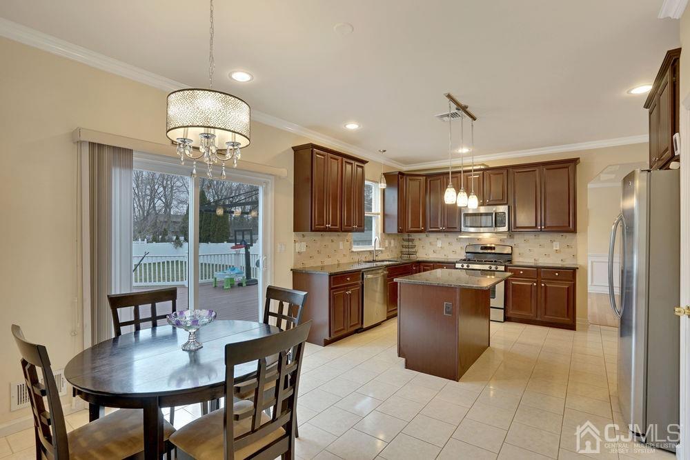 41 Middlesex Road Old Bridge, NJ 07747 - Photo 22 of 40 a kitchen with stainless steel appliances granite countertop a stove a refrigerator a kitchen island a sink dishwasher a dining table and chairs with wooden floor