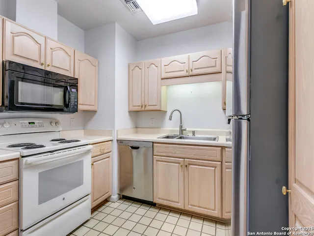a kitchen with cabinets stainless steel appliances and sink