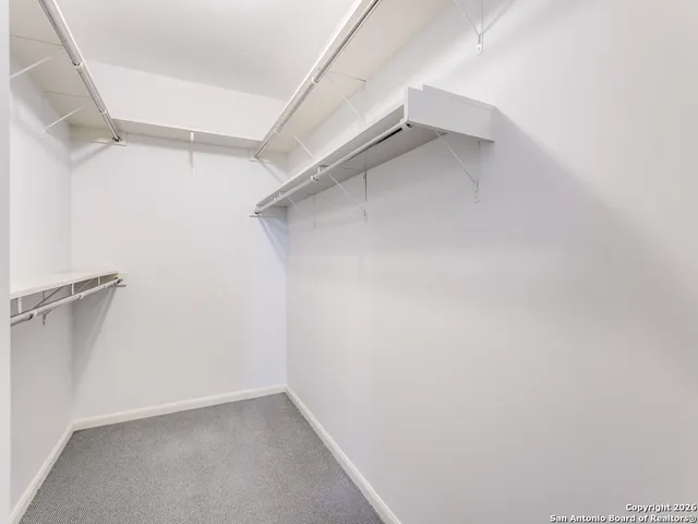 an empty room with chandelier fan and windows