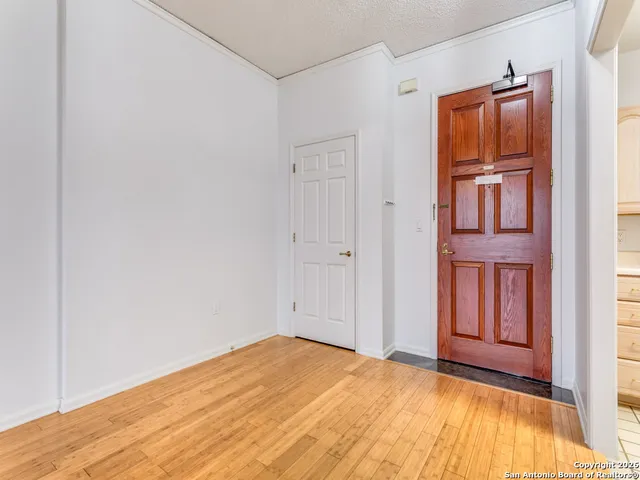 a view of an empty room with a window and wooden floor