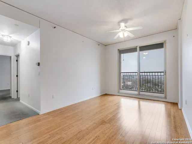 a view of an empty room with wooden floor and a window