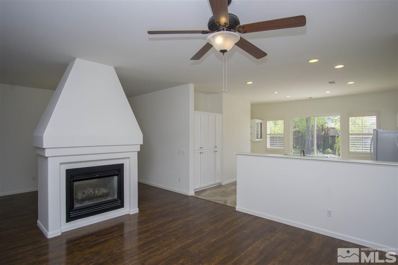 10598 Eagle Falls Way Reno, NV 89521 - Photo 5 of 17 an empty room with wooden floor a ceiling fan and a fireplace