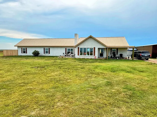 a view of a house with a big yard and large trees