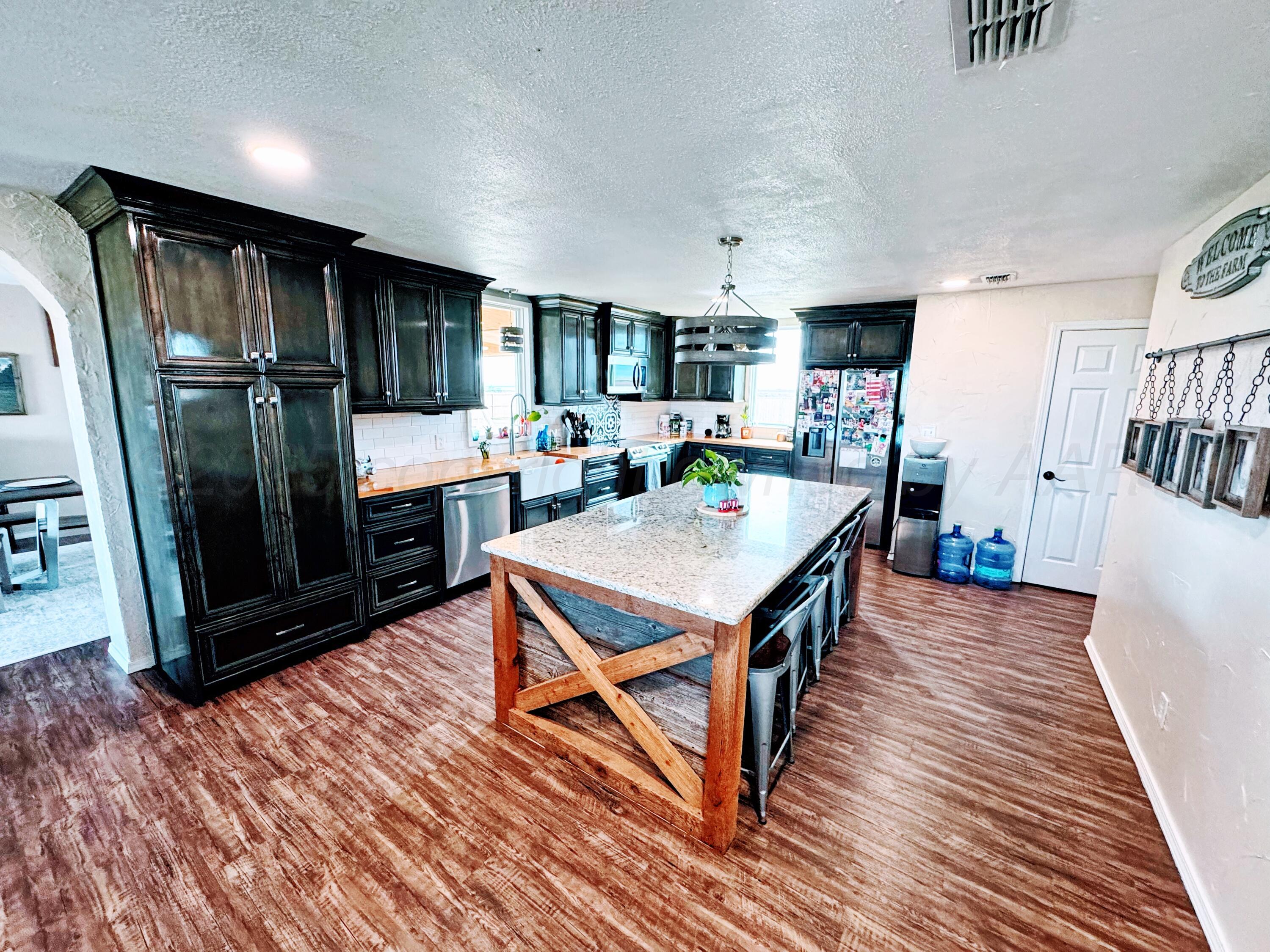 14155 County Road 7 Perryton, TX 79070 - Photo 5 of 25 a open kitchen with stainless steel appliances a dining table chairs and wooden floor