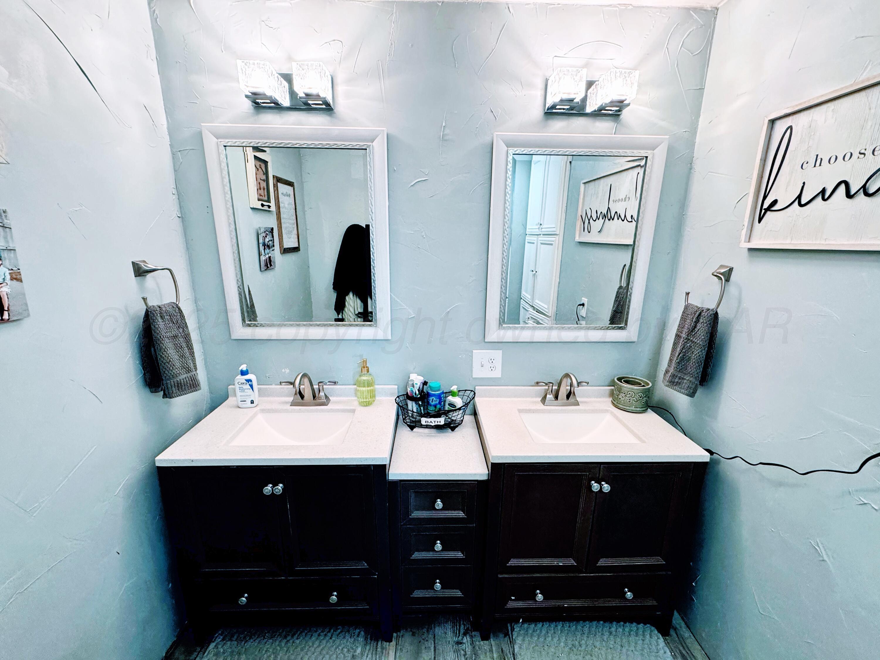 14155 County Road 7 Perryton, TX 79070 - Photo 9 of 25 a bathroom with double vanity sinks and a mirror