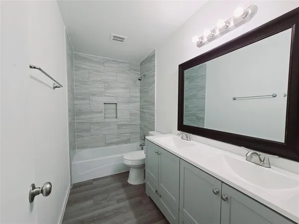 a bathroom with a double vanity sink toilet mirror and bathtub